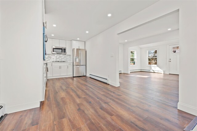 kitchen with white cabinets, open floor plan, light countertops, appliances with stainless steel finishes, and baseboard heating