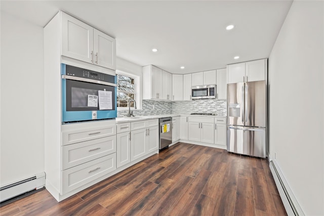 kitchen with stainless steel appliances, baseboard heating, a sink, and white cabinetry