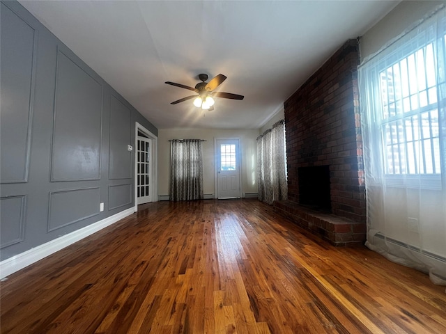 unfurnished living room with hardwood / wood-style floors, a fireplace, a baseboard radiator, and ceiling fan