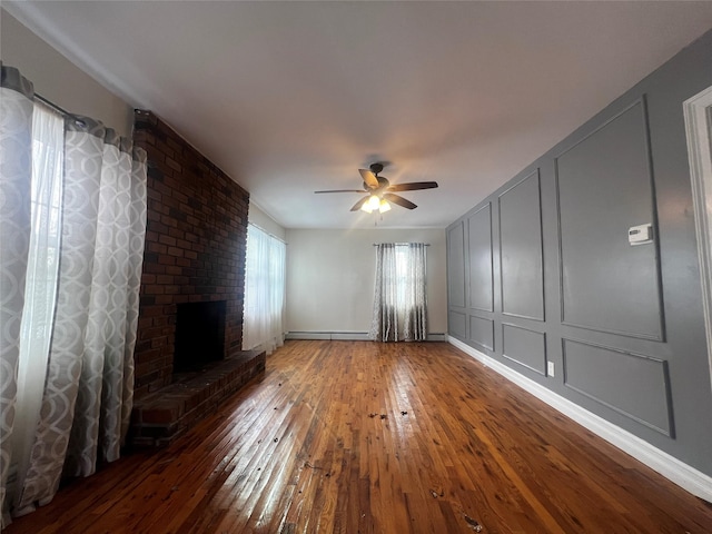 unfurnished living room featuring ceiling fan, a baseboard radiator, wood-type flooring, and a brick fireplace