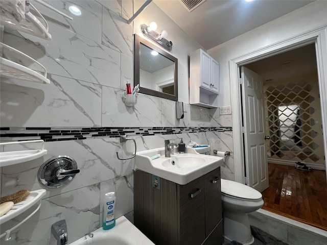 bathroom featuring vanity, a bathing tub, and toilet