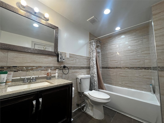 full bathroom with vanity, toilet, shower / bath combo with shower curtain, and tile walls