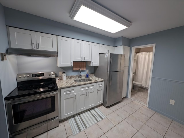 kitchen with light tile patterned flooring, appliances with stainless steel finishes, sink, and white cabinets