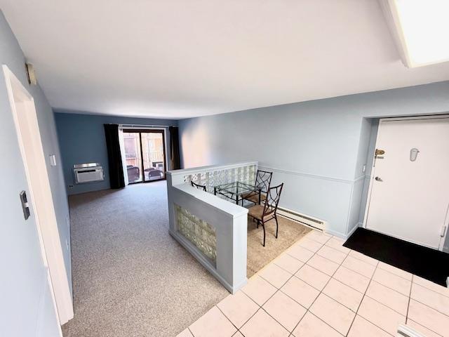 corridor featuring a baseboard heating unit and light colored carpet