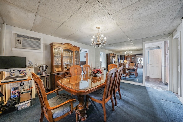 carpeted dining area featuring a drop ceiling, a wall unit AC, and a chandelier