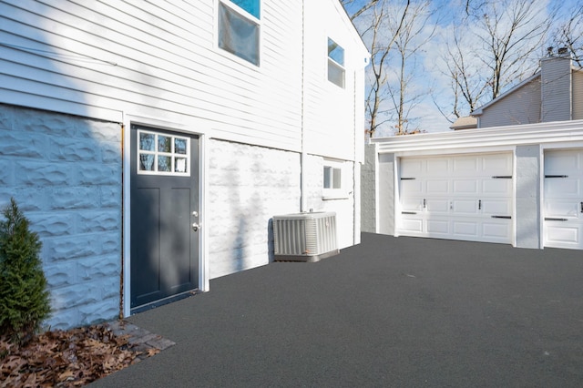 view of side of home with a garage and cooling unit