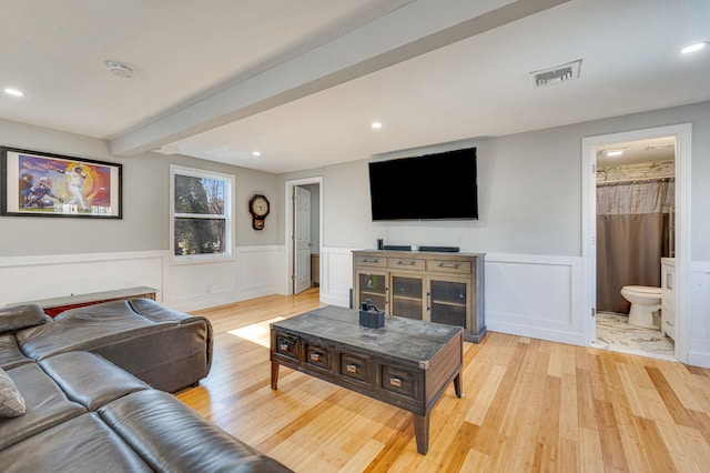 living room with beamed ceiling and light wood-type flooring