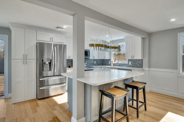 kitchen featuring a kitchen island, appliances with stainless steel finishes, white cabinetry, sink, and a breakfast bar area