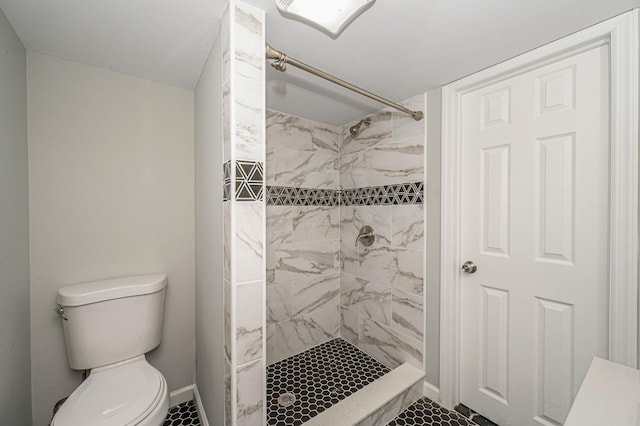 bathroom with a tile shower and toilet