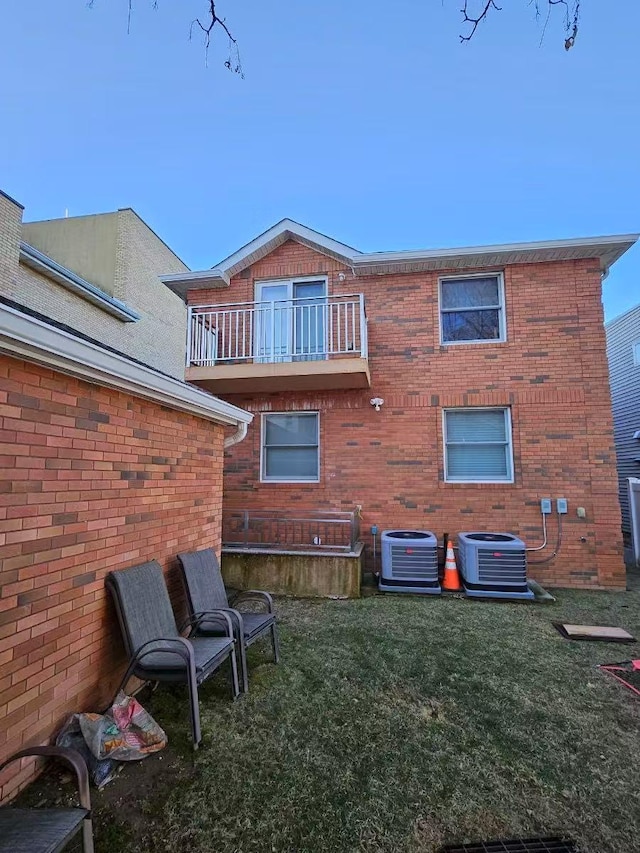 rear view of house with a balcony, a lawn, and central air condition unit