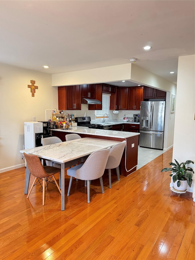 kitchen with appliances with stainless steel finishes, sink, and light hardwood / wood-style flooring