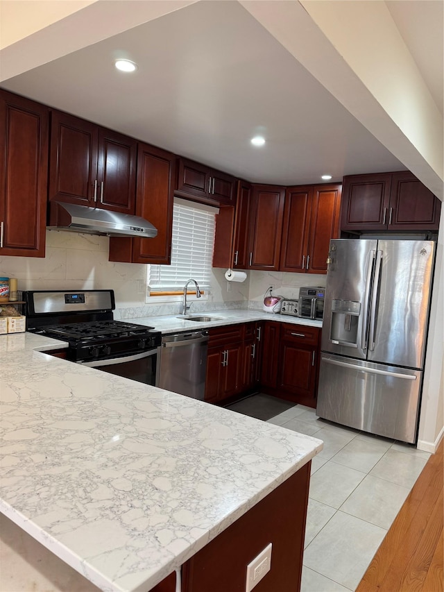 kitchen with sink, light tile patterned floors, light stone counters, kitchen peninsula, and stainless steel appliances