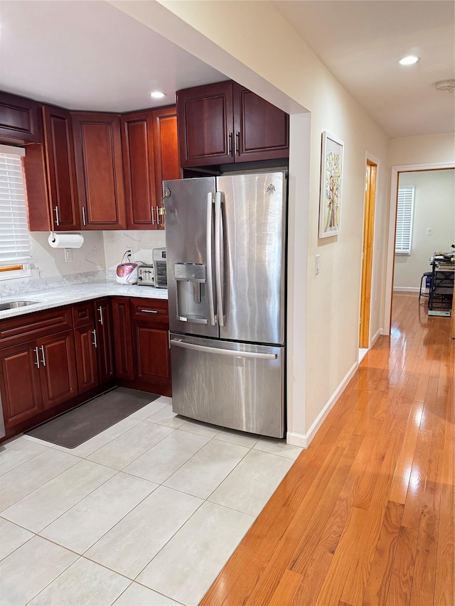 kitchen featuring stainless steel fridge with ice dispenser, sink, and light wood-type flooring