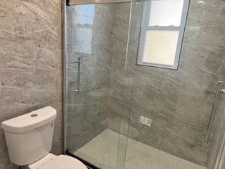 bathroom with toilet and a shower with shower door