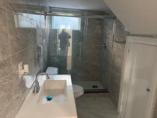 bathroom with vanity, toilet, an enclosed shower, and tile walls