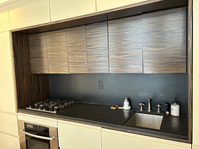 kitchen with gas stovetop, sink, oven, and backsplash