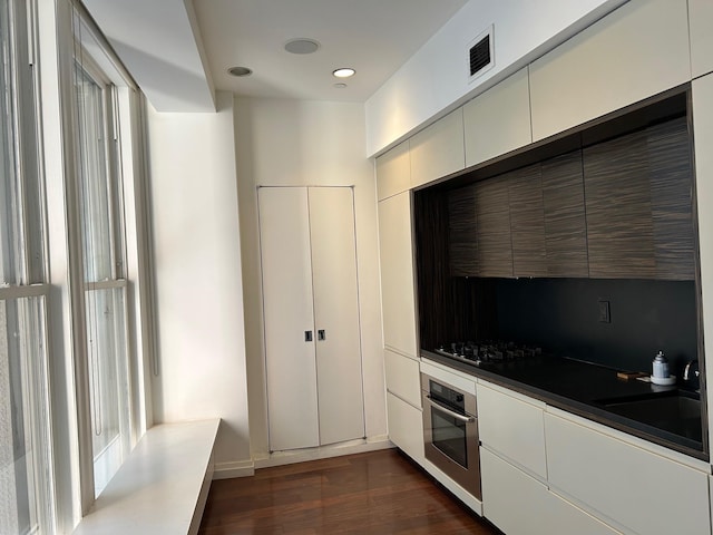 kitchen featuring dark wood-type flooring, sink, gas cooktop, oven, and white cabinets