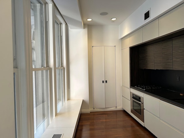 kitchen with white cabinetry, dark wood-type flooring, stainless steel oven, and black gas cooktop