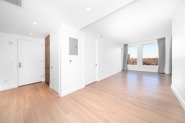 empty room with light hardwood / wood-style flooring and electric panel