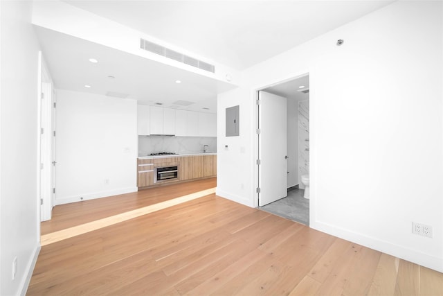 unfurnished living room with light hardwood / wood-style flooring, electric panel, and a tile fireplace