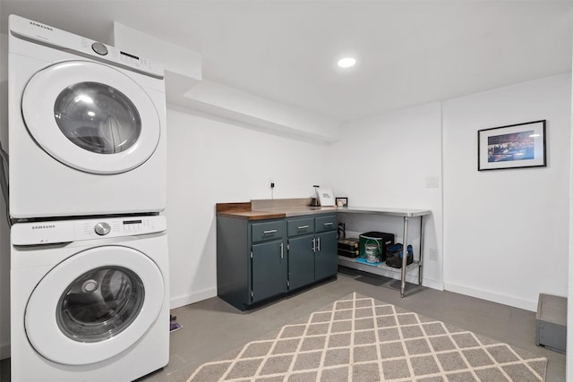 washroom with stacked washer / dryer and cabinets