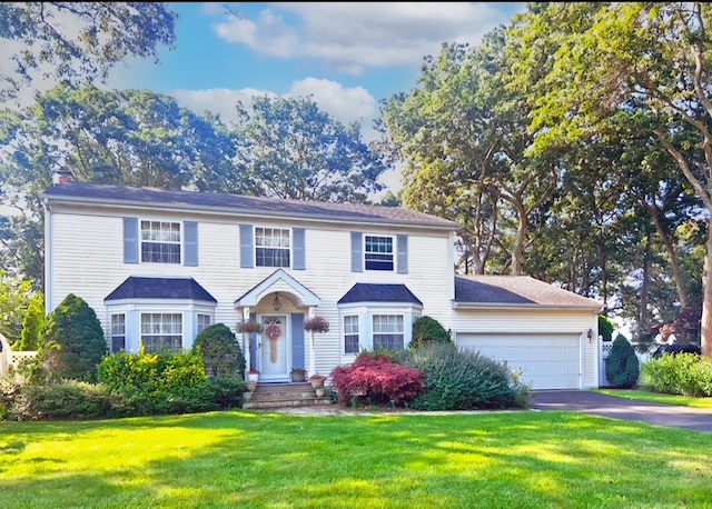 colonial inspired home with a garage and a front yard