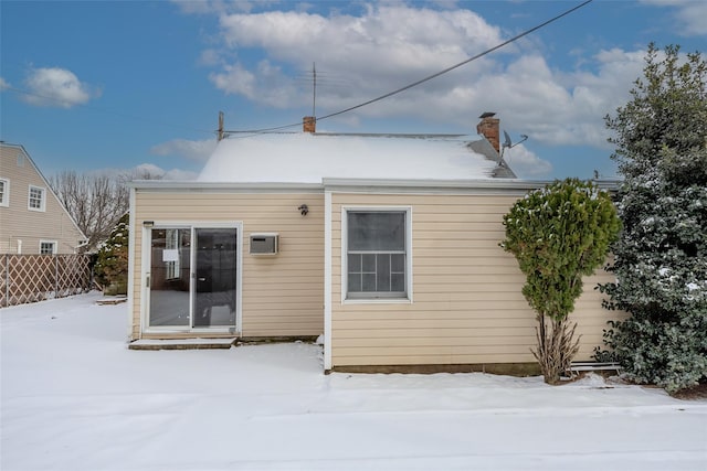 snow covered house featuring a wall mounted AC