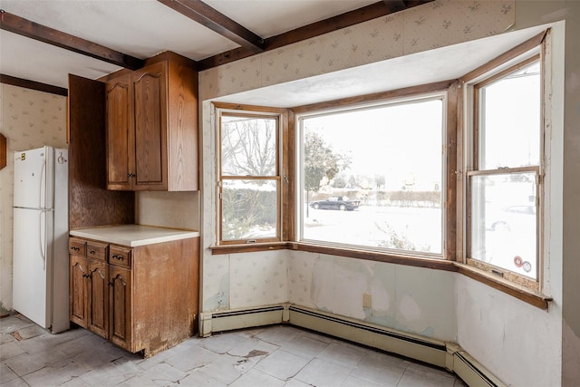 kitchen with beamed ceiling, a baseboard radiator, white fridge, and a wealth of natural light