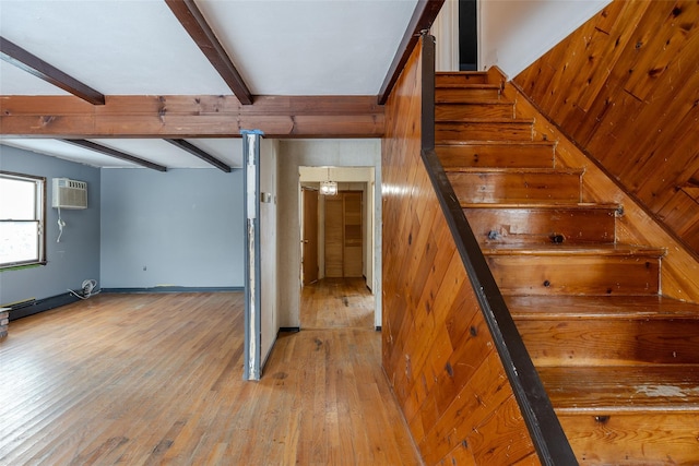 stairs featuring beam ceiling, wood-type flooring, and a wall mounted AC