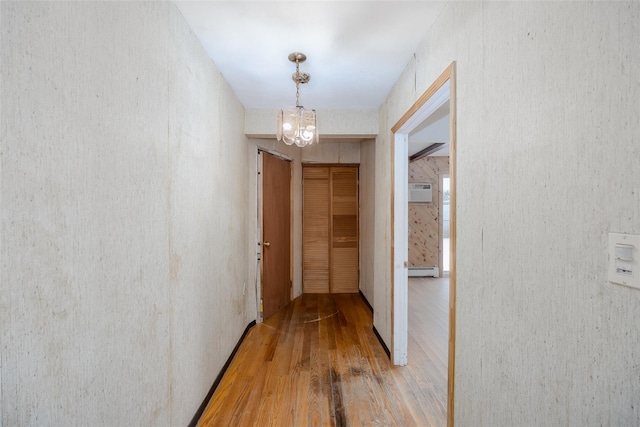 corridor featuring a baseboard heating unit, hardwood / wood-style flooring, and a chandelier