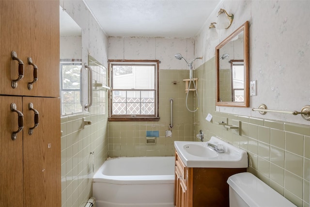 full bathroom featuring vanity, toilet, tiled shower / bath combo, and tile walls