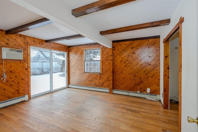 spare room with beam ceiling, a wall unit AC, and light hardwood / wood-style flooring