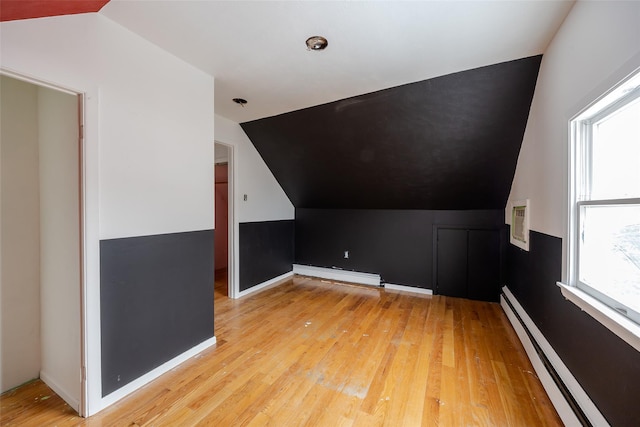 additional living space with baseboard heating, lofted ceiling, and light hardwood / wood-style floors