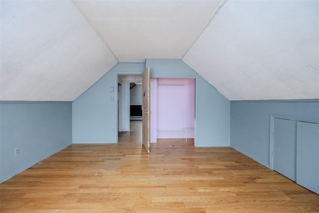 bonus room with a baseboard radiator, lofted ceiling, and light hardwood / wood-style flooring