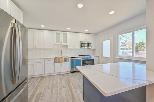 kitchen with white cabinetry, appliances with stainless steel finishes, sink, and light stone counters