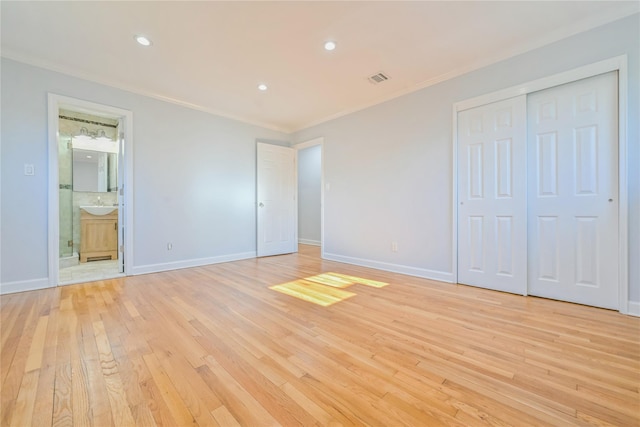 unfurnished bedroom with ornamental molding, a closet, and light wood-type flooring