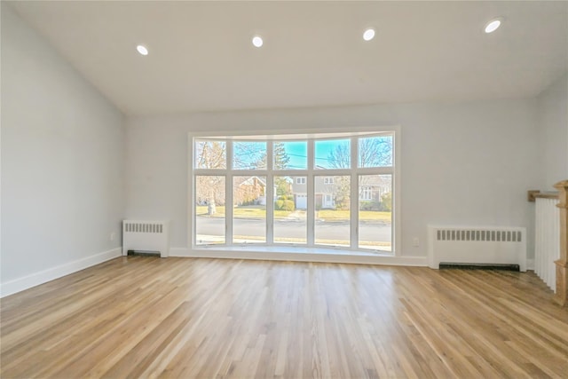 unfurnished living room featuring radiator heating unit and light hardwood / wood-style flooring