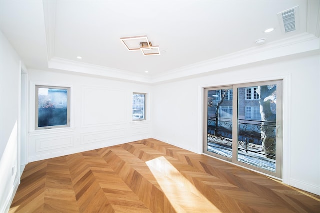 unfurnished room with parquet floors, a tray ceiling, and ornamental molding