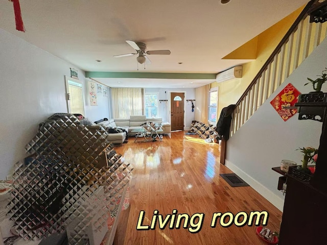 living room with hardwood / wood-style flooring, an AC wall unit, and ceiling fan