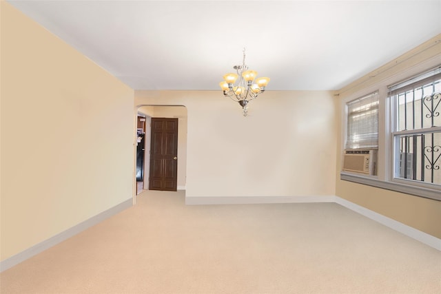 spare room with cooling unit, carpet flooring, and a chandelier