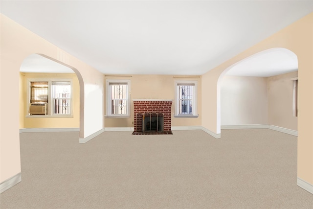 unfurnished living room with cooling unit, light colored carpet, and a fireplace