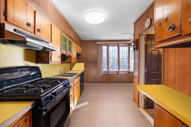 kitchen featuring wood walls, sink, light tile patterned floors, ceiling fan, and black appliances