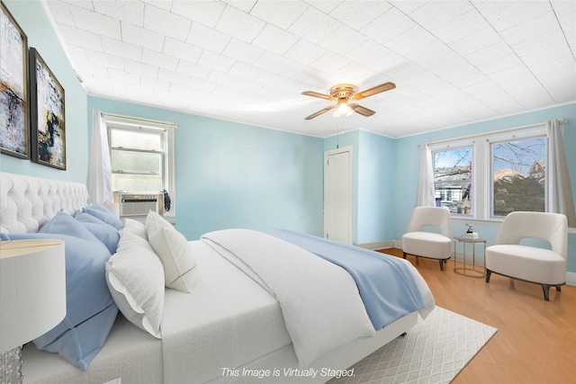 bedroom featuring multiple windows, cooling unit, light hardwood / wood-style floors, and ceiling fan