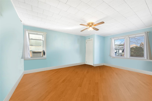 empty room featuring cooling unit, plenty of natural light, light hardwood / wood-style floors, and ceiling fan