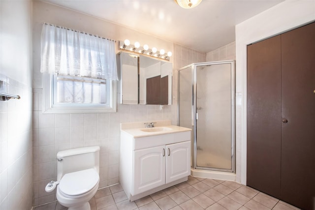 bathroom with walk in shower, tile patterned floors, toilet, tile walls, and vanity