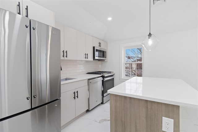 kitchen featuring decorative light fixtures, stainless steel appliances, a center island, and white cabinets