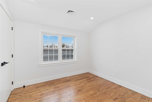 empty room featuring vaulted ceiling and light hardwood / wood-style floors