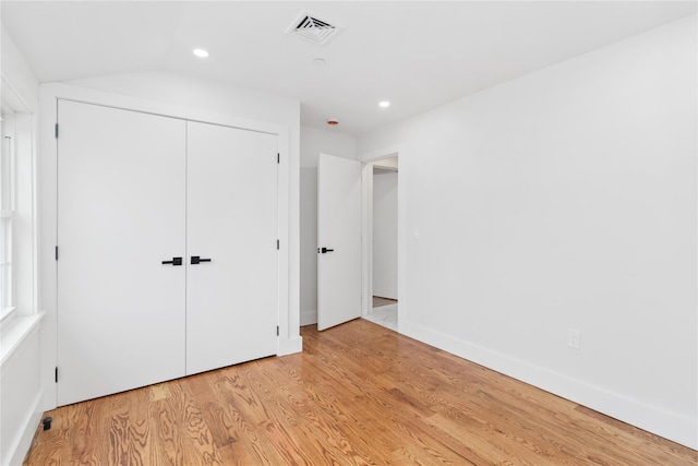 unfurnished bedroom with a closet, vaulted ceiling, and light hardwood / wood-style flooring