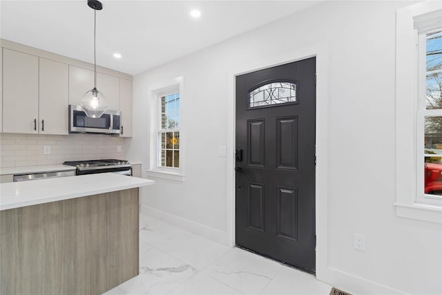 kitchen featuring pendant lighting, decorative backsplash, plenty of natural light, and stainless steel appliances