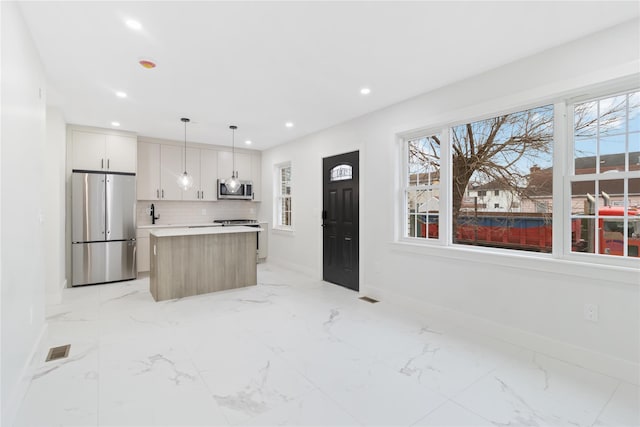 kitchen with decorative light fixtures, white cabinetry, backsplash, a center island, and stainless steel appliances